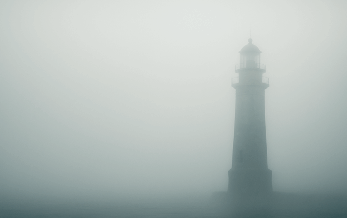 Leuchtturm im dichten Nebel mit freier Fläche auf der linken Seite