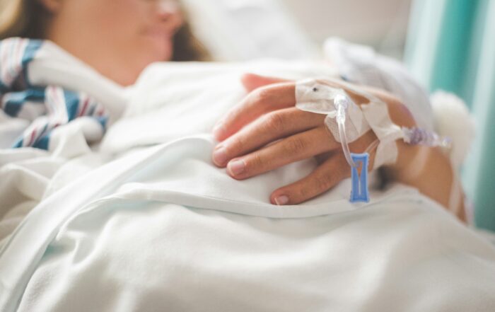 Patientin liegt in einem Klinikbett und erhält medizinische Versorgung