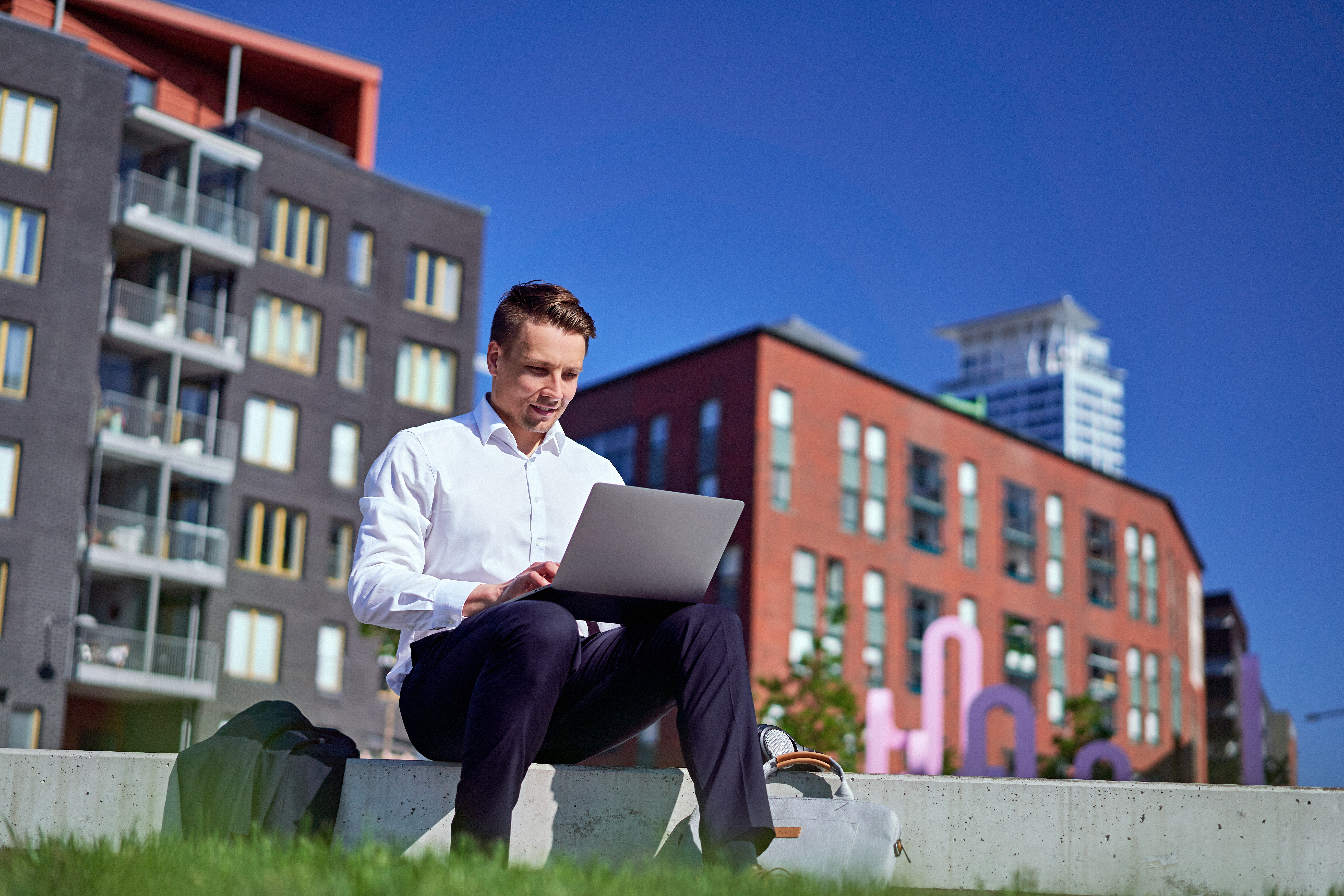 Business Finland: Digitales Arbeiten im urbanen Umfeld Business-Motiv mit Mann am Laptop vor moderner Architektur