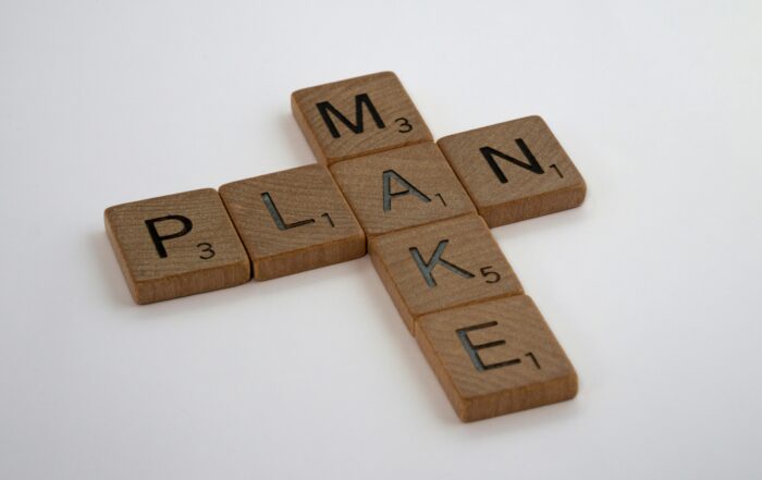 Holzbuchstaben mit den Wörtern „PLAN“ und „MAKE“ als Symbol für strategische Kommunikation und Umsetzung